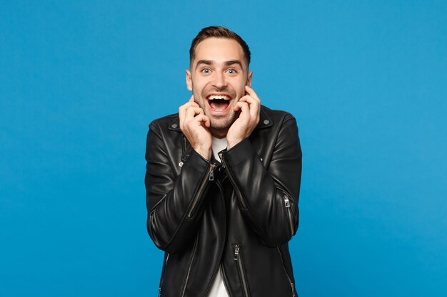 Hübscher, stilvoller junger, unrasierter Mann in schwarzer Lederjacke, weißem T-Shirt, der Kamera isoliert auf blauem Wandhintergrund-Studioporträt sieht. Menschen aufrichtige Emotionen Lifestyle-Konzept. Mock-up-Kopierraum