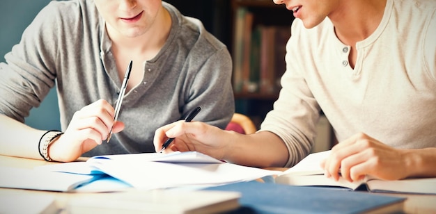 Hübscher Student, der an einem Aufsatz in der Bibliothek arbeitet