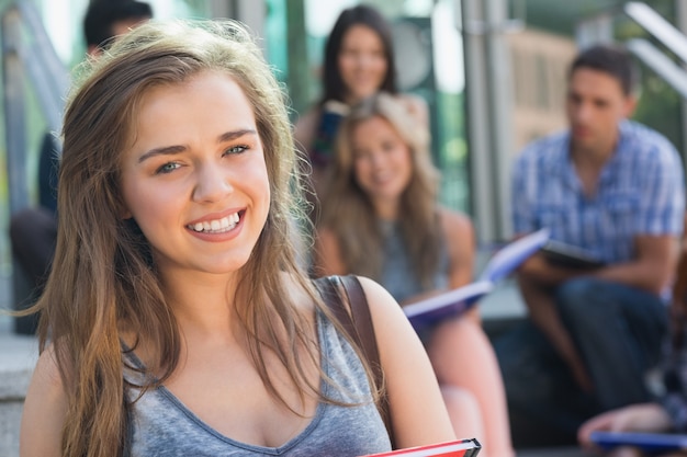 Foto hübscher student, der draußen an der kamera lächelt