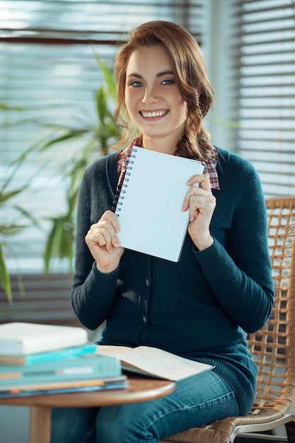 Hübscher Student, der ein leeres Notizbuch zeigt