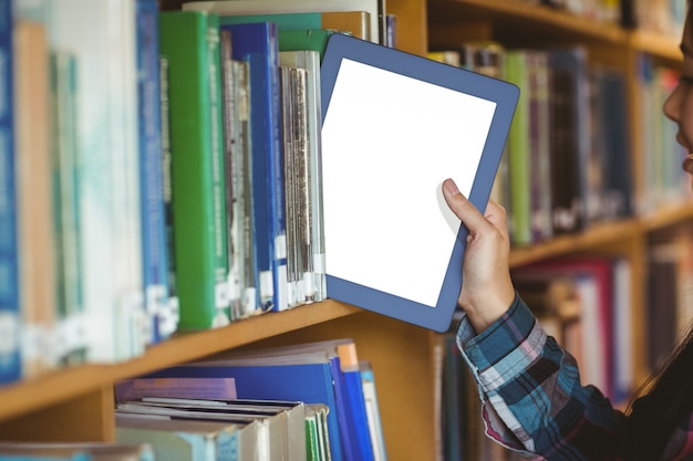 Hübscher Student, der Tabelle in Bücherregal setzt