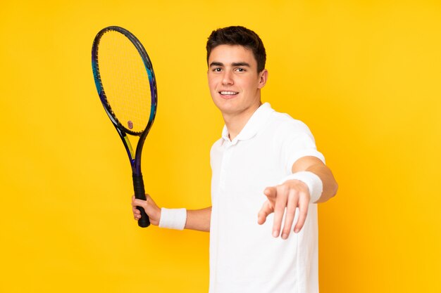 Hübscher Teenager-Tennisspieler Mann auf gelber Wand, die Tennis spielt