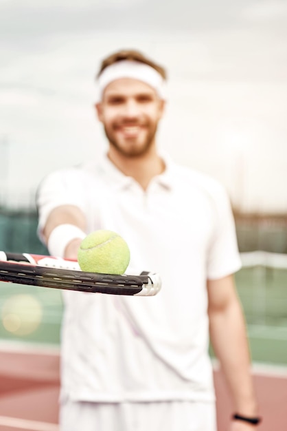 Hübscher Tennisspieler mit einem Schläger auf einem Platz