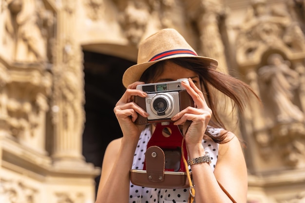 Hübscher Tourist mit Hut, der die Kirche mit Fotokamera besucht und das Frühlings- oder Sommerferienkonzept der weiblichen Reisenden und Erstellerin digitaler Inhalte genießt