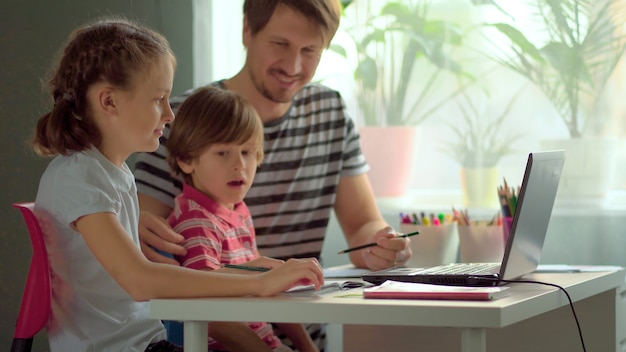 Foto hübscher vater, der seinen kindern bei den hausaufgaben hilft