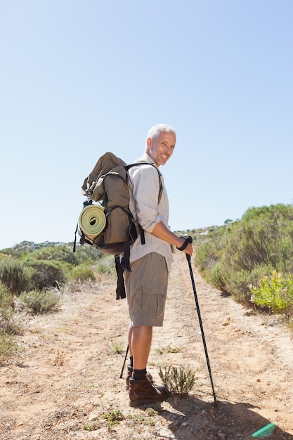 Hübscher Wanderer, der an der Kamera in der Landschaft lächelt