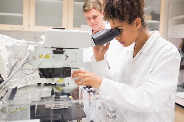 Hübscher Wissenschaftsstudent, der Mikroskop verwendet