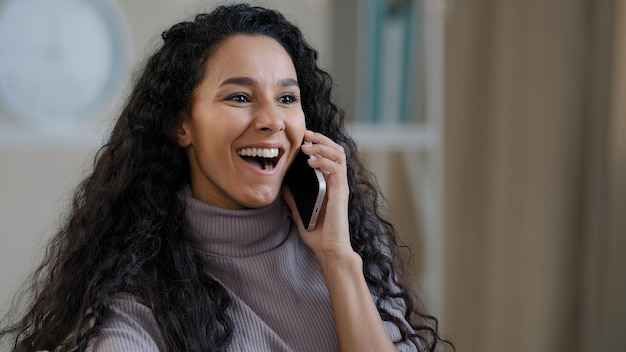 Hübsches arabisches lächelndes Mädchen junge Dame, die per Handy spricht, genießt drahtlose Gespräche und erzählt Klatsch