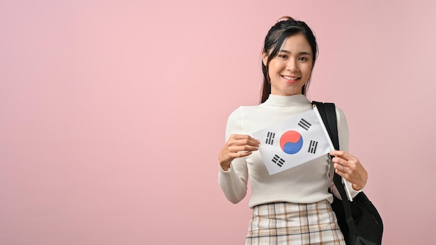 Foto hübsches asiatisches mädchen, das eine südkorea-flagge auf rosa isoliertem hintergrund-bildungskonzept zeigt