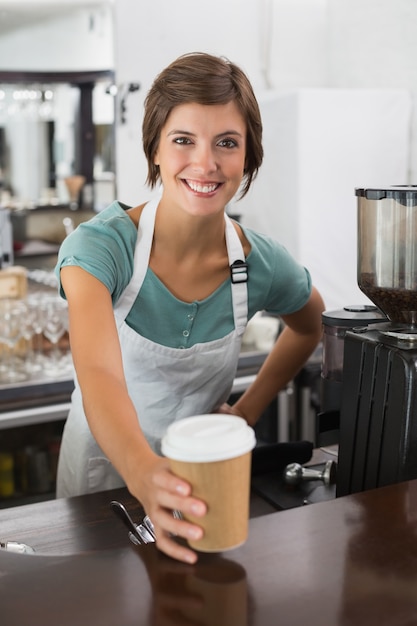 Hübsches barista, das an der Kamera hält Wegwerfschale lächelt