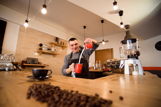 Hübsches barista, das tasse kaffee für kunden in der kaffeestube zubereitet.