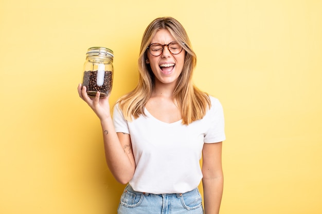 Hübsches blondes Mädchen, das aggressiv schreit und sehr wütend aussieht. Kaffeebohnen-Konzept