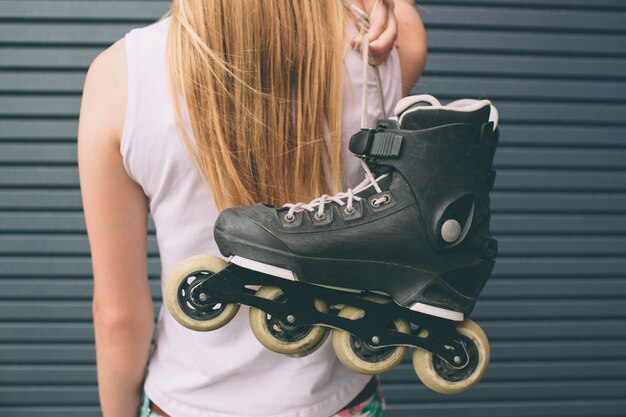 Hübsches blondes Mädchen, das mit Rollschuhen draußen aufwirft. Sommerlebensstilporträt