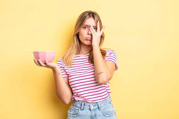 hübsches blondes mädchen, das sich nach einer ermüdenden müdigkeit gelangweilt, frustriert und schläfrig fühlt. Konzept der leeren Schüssel