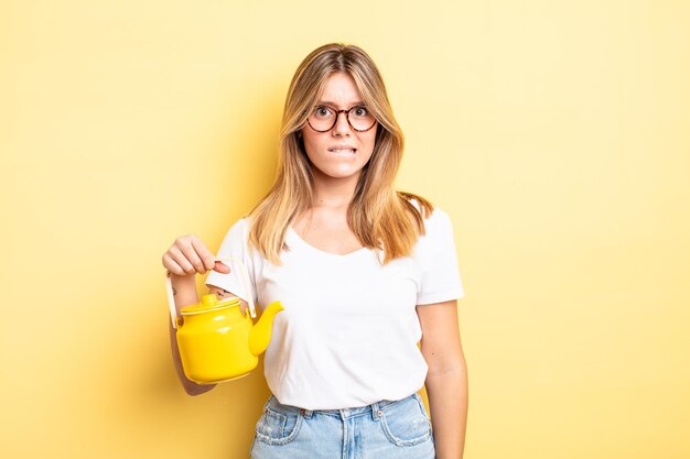 Foto hübsches blondes mädchen, das verwirrt und verwirrt aussieht. teekanne-konzept