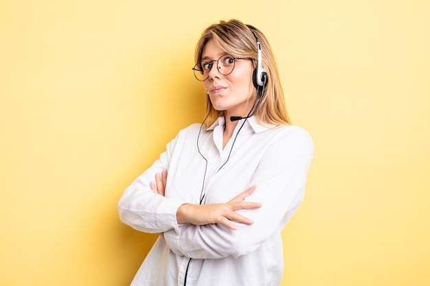 Hübsches blondes Mädchen zuckt mit den Schultern, fühlt sich verwirrt und unsicher. Headset-Konzept