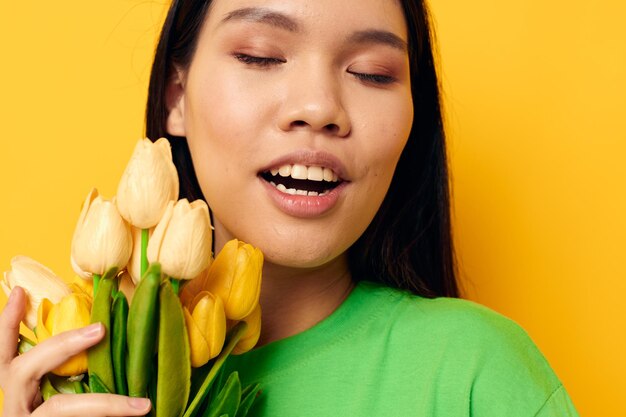 Hübsches brünettes grünes T-Shirt ein Strauß gelber Blumen isolierter Hintergrund unverändert