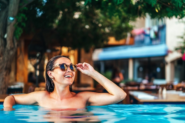 Hübsches Brunettemädchen, das am Swimmingpool sich entspannt