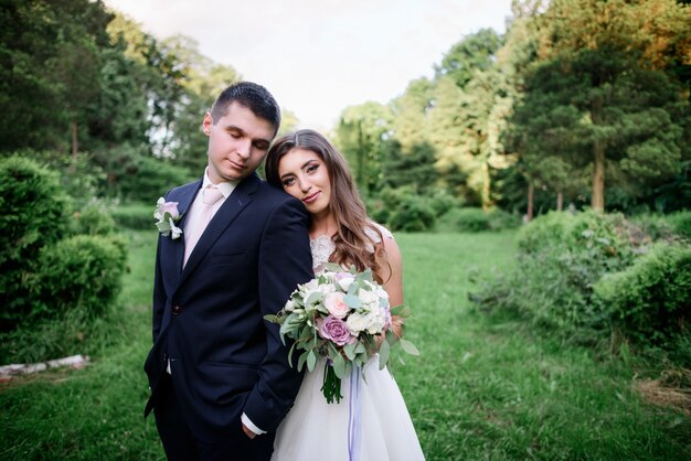 Hübsches Hochzeitspaar wirft in einem grünen Frühlingsgarten auf