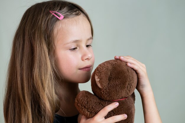 Hübsches Kindermädchen, das mit ihrem Teddybärspielzeug spielt.