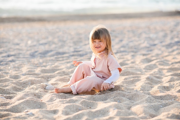 Hübsches kleines Kind, das am Strand über Meer spielt