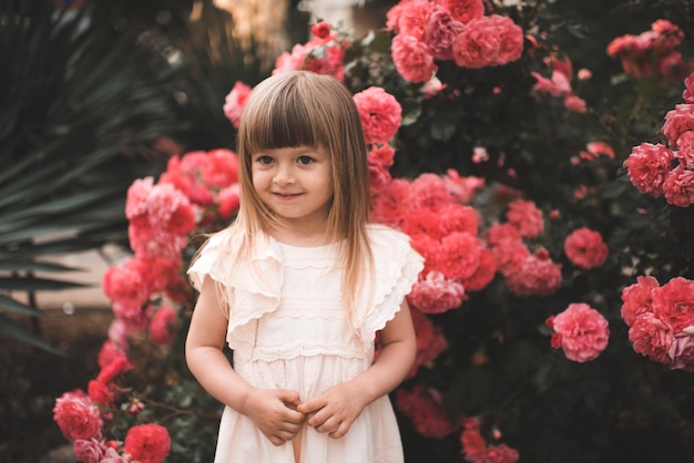 Hübsches kleines Kindermädchen mit blühenden rosa Blumen im Park draußen