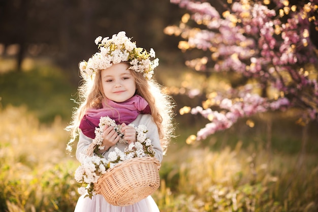 Hübsches kleines Kindermädchen mit Blumen über blühendem Naturhintergrund