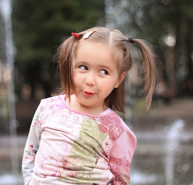 Hübsches kleines Mädchen auf dem Hintergrund des Stadtbrunnens.