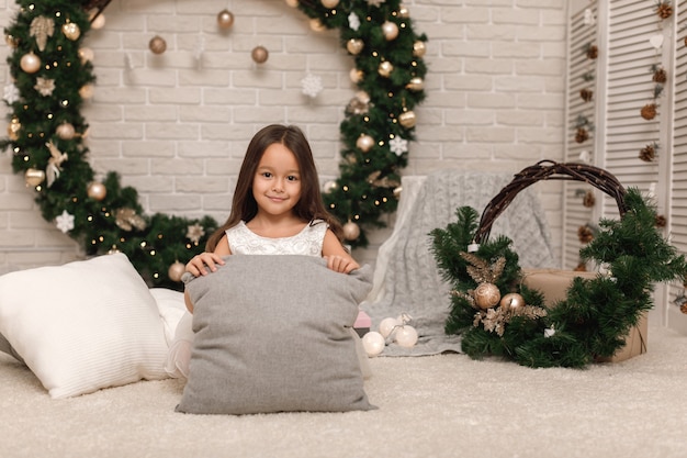 Hübsches kleines Mädchen in einem weißen Kleid an Weihnachten