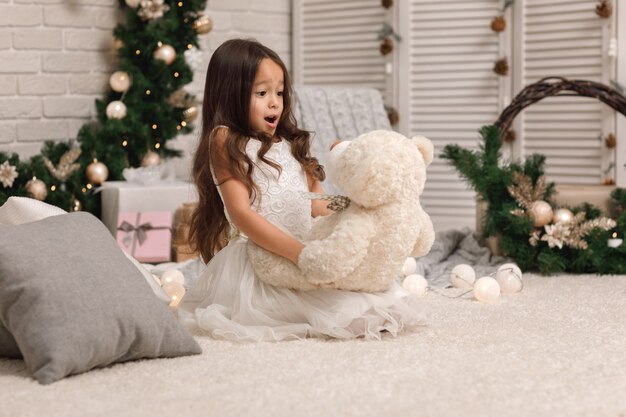 Hübsches kleines Mädchen mit einem Teddybär an Weihnachten