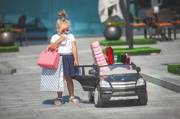 Hübsches kleines Mädchen mit Einkaufstüten in einem Minicar