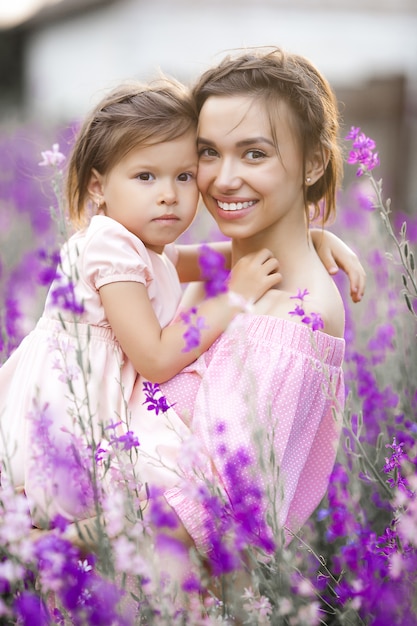 Hübsches kleines Mädchen und ihre Mutter mit Blumen. Familie im Freien