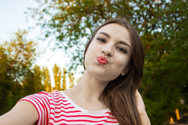 Hübsches lächelndes Mädchen, das selfie, langhaarigen Brunette in der weißen Kleidung macht