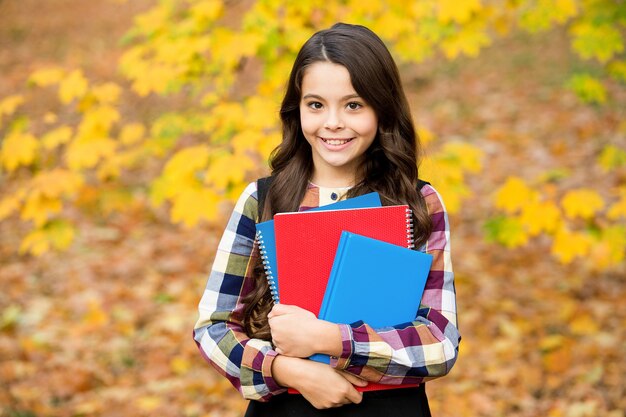 Hübsches lächelndes Mädchen halten Notizbücher und Bücher, Schule.