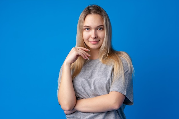 Hübsches lächelndes Mädchenporträt vor blauem Hintergrund im Studio