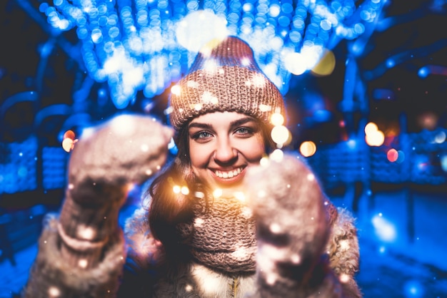 Hübsches Mädchen auf der Straße mit Weihnachtslichtern herum