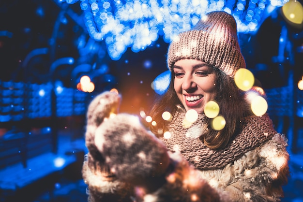 Hübsches Mädchen auf der Straße mit Weihnachtslichtern herum