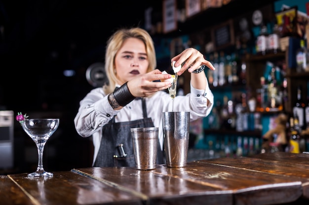 Hübsches Mädchen Barkeeper macht einen Cocktail, während in der Nähe der Theke im Nachtclub stehen