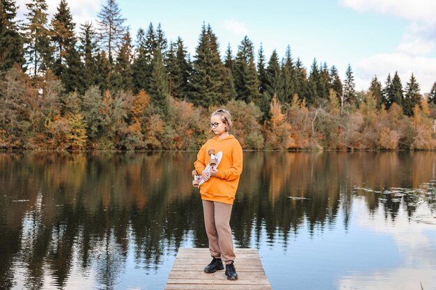 Hübsches Mädchen, das an einem schönen Herbsttag im Freien Skateboard lernt. Kinderaktivitäten und aktives Lifestyle-Konzept.