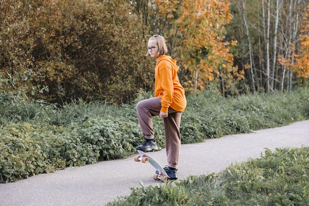 Hübsches Mädchen, das an einem schönen Herbsttag im Freien Skateboard lernt. Kinderaktivitäten und aktives Lifestyle-Konzept.