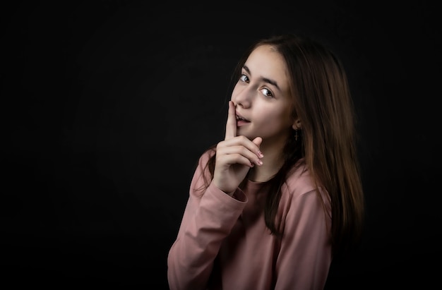 Hübsches Mädchen, das im Studio mit ihrem Zeigefinger auf ihren Lippen aufwirft