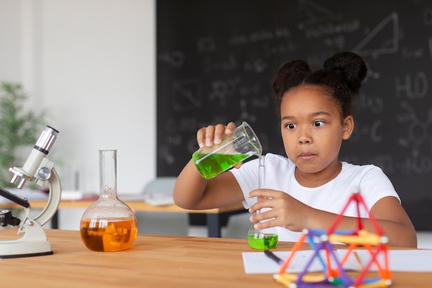 Foto hübsches mädchen, das im unterricht mehr über chemie lernt