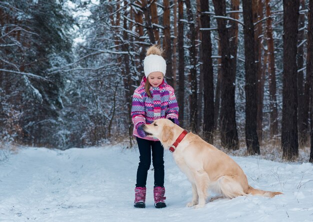 Hübsches Mädchen, das mit ihrem Hund an einem Wintertag spielt