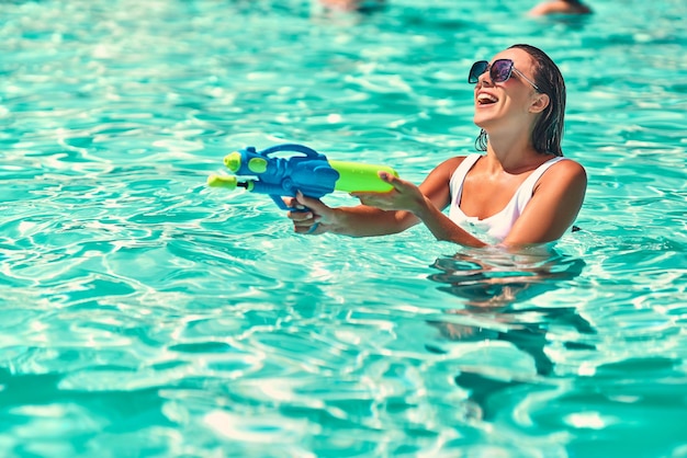 Hübsches Mädchen, das mit Wasserpistolen im Pool spielt