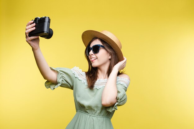 Hübsches Mädchen im Hut und im Sommerkleid, das selfie vor der Kamera nimmt.