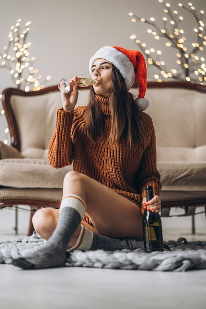 Hübsches Mädchen im Pullover und in der Weihnachtsmütze, die Champagner trinken