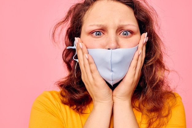 Hübsches Mädchen in einem gelben T-Shirt medizinische Maske Schutz rosa Hintergrund unverändert