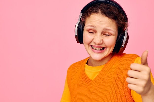 Hübsches Mädchen in einem orangefarbenen Pullover Kopfhörer Musik Unterhaltung beschnittene Ansicht unverändert Foto in hoher Qualität