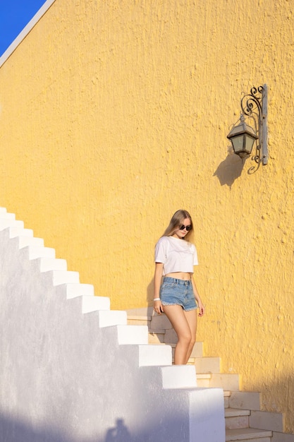 Hübsches Mädchen kommt die Treppe hinunter Blonde Frau mit langen Haaren geht die weiße Treppe vor dem Hintergrund hinauf