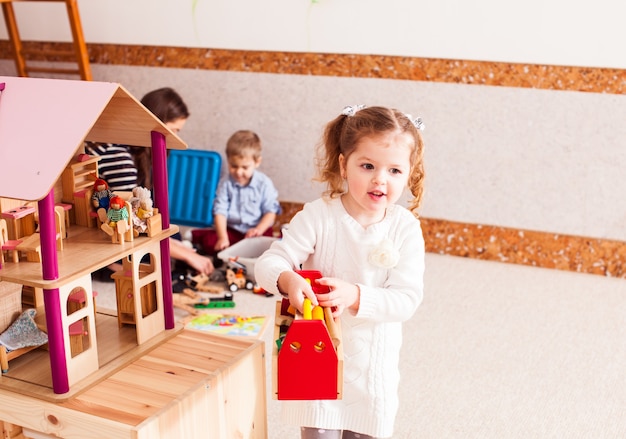 Hübsches Mädchen repariert das Dach des Puppenhauses im Kindergarten